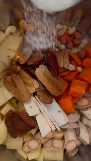Ingredients to make burdock root soup in the inner pot of an Instant Pot, with salted added on top.