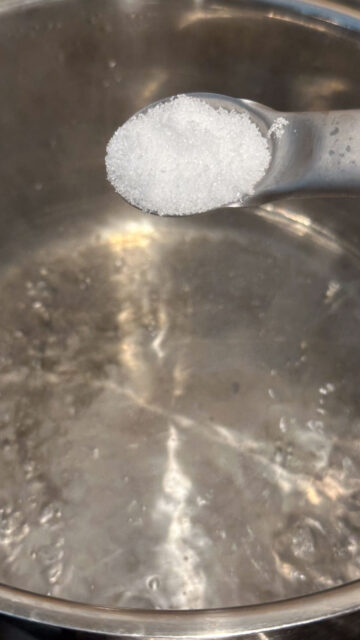 A teaspoonful of salt held over a pot of boiling water.