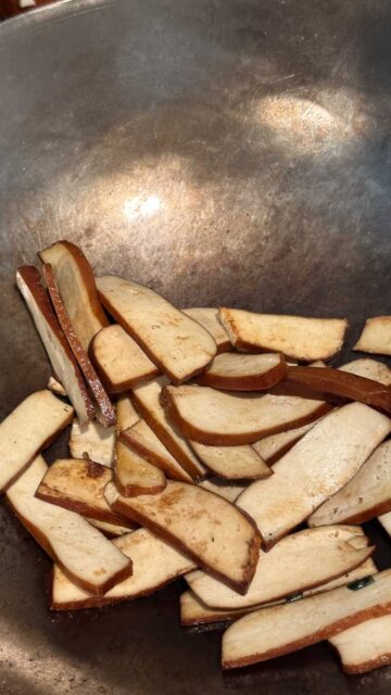 Bean curd slices cooking in a wok, slightly browned.