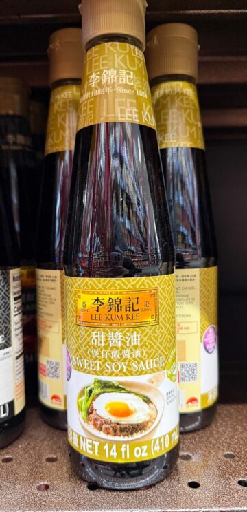 A bottle of Lee Kum Kee Sweet Soy Sauce, 14 fl oz, on a store shelf, with others in the background.