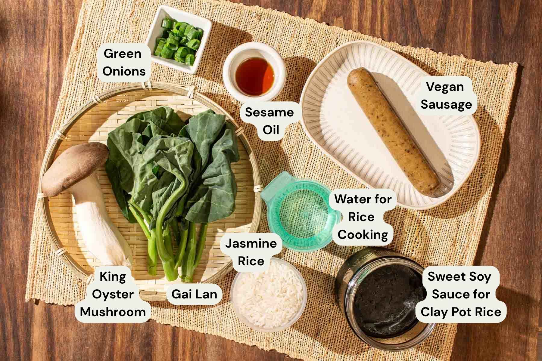 Ingredients required to make rice cooker vegan clay pot rice: King oyster mushroom, gai lan, jasmine rice, water for rice cooking, sweet soy sauce for clay pot rice, vegan sausage, green onions, and sesame oil.