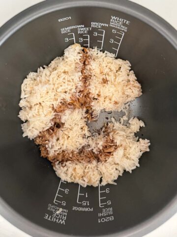 Cooked white rice with drizzled sweet soy sauce in a rice cooker pot.