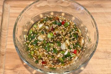 The dressing for bitter melon salad in a glass bowl on a wooden surface.