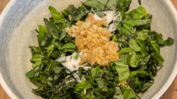 Chopped basil leaves, minced garlic, minced ginger, sugar, and salt in a white bowl.