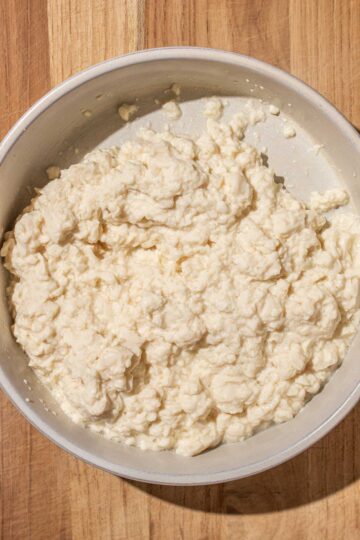 A bowl of mashed silken tofu, on a wooden surface.