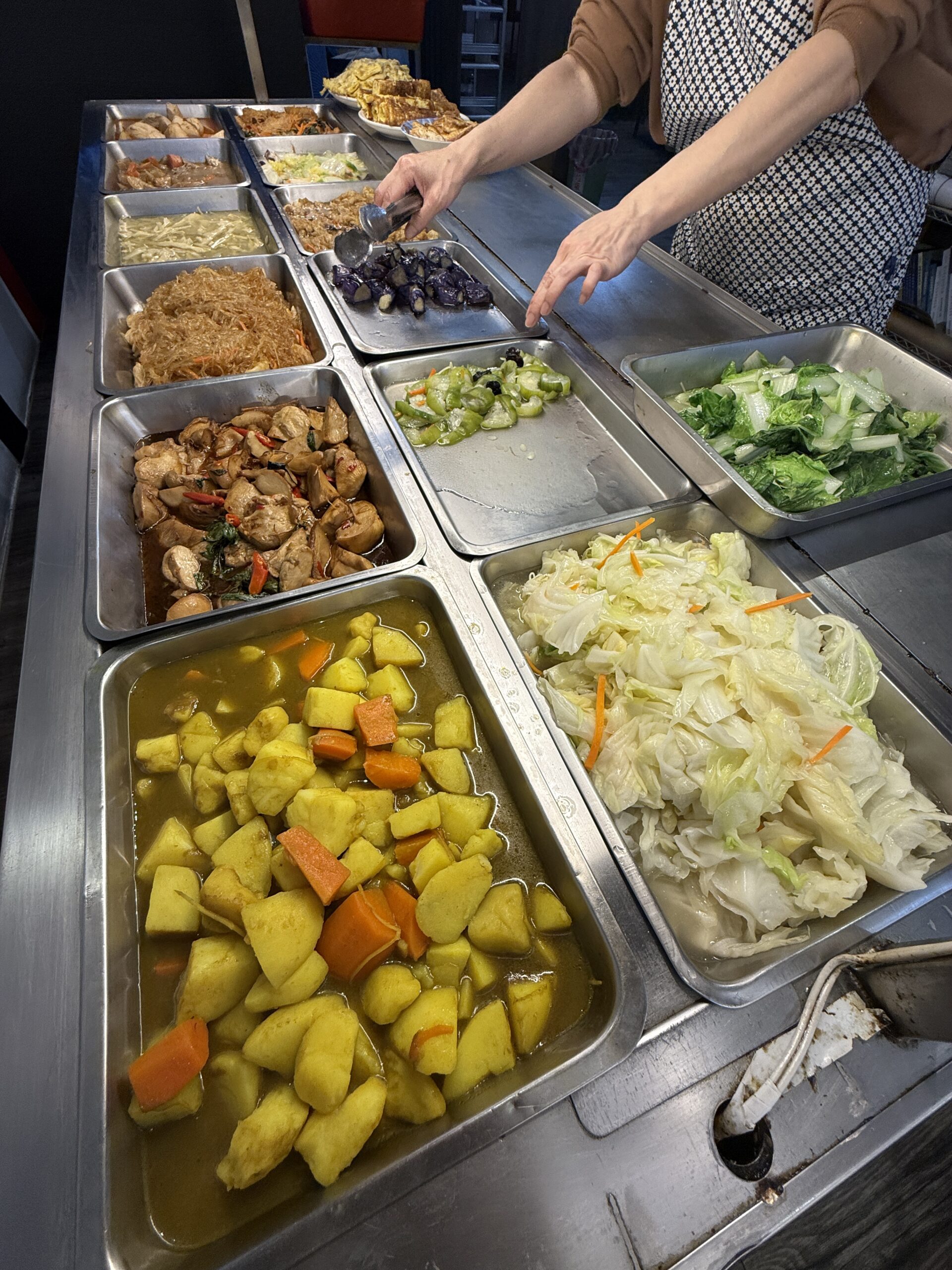 A self-service vegetarian buffet with various options served in metal trays.