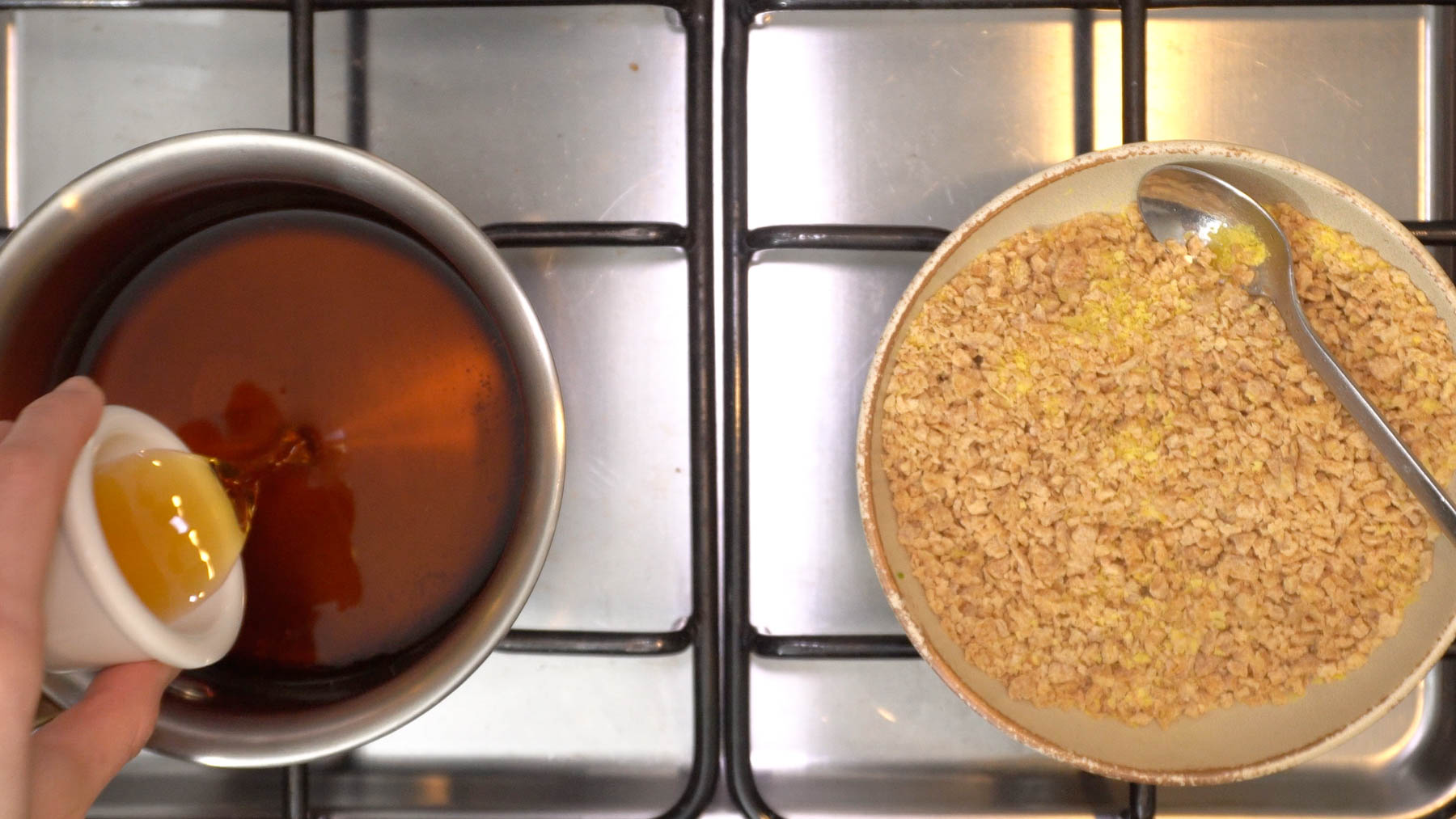 A hand pours Shaoxing wine into a pot of marinating liquid, next to a bowl of Textured Vegetable Protein (TVP) and nutritional yeast, on a stovetop.