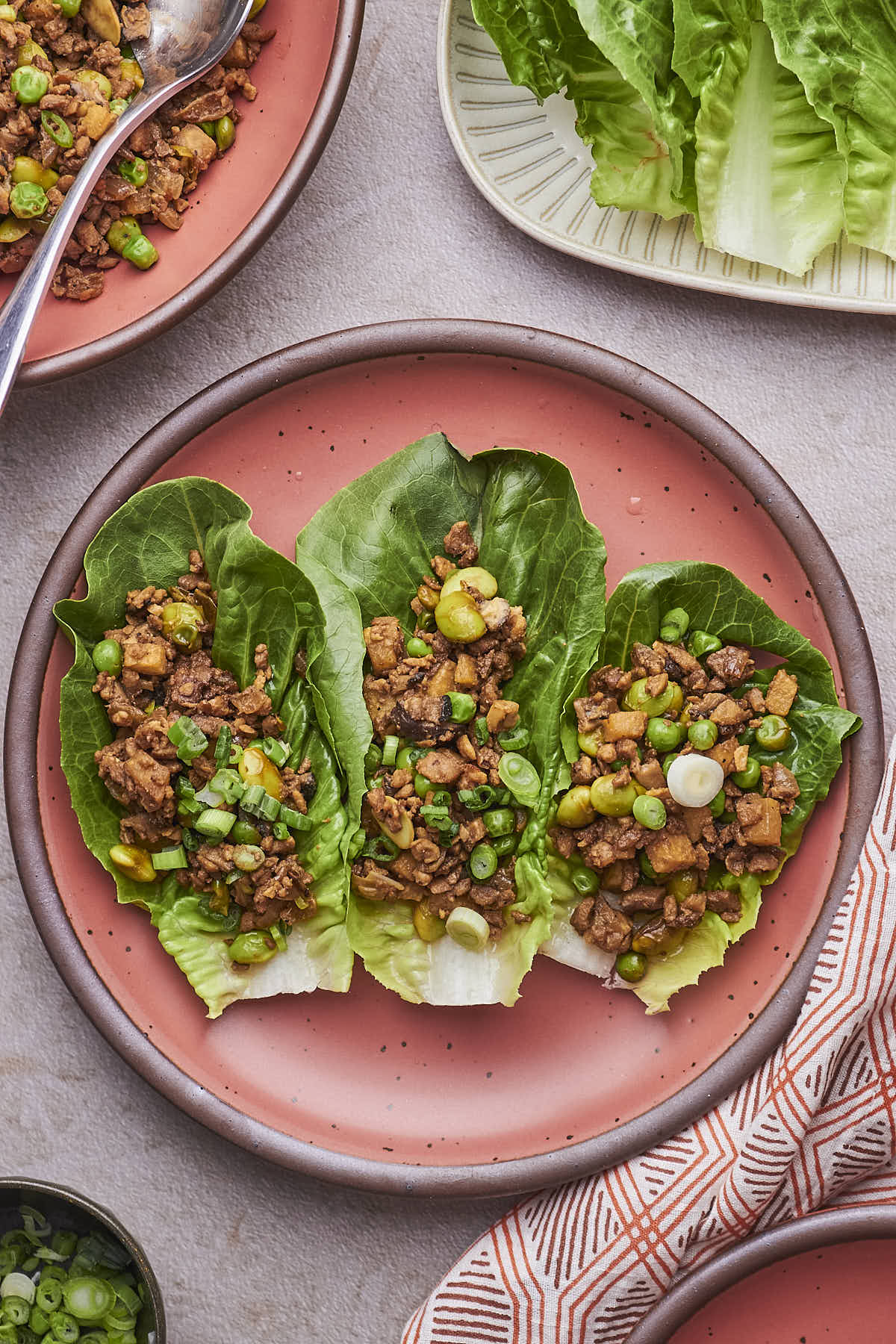 Three Vegetarian Lettuce Wraps loaded with seasoned TVP-based filling, served on a pink plate.