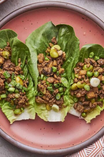 Three Vegetarian Lettuce Wraps loaded with seasoned TVP-based filling, served on a pink plate.