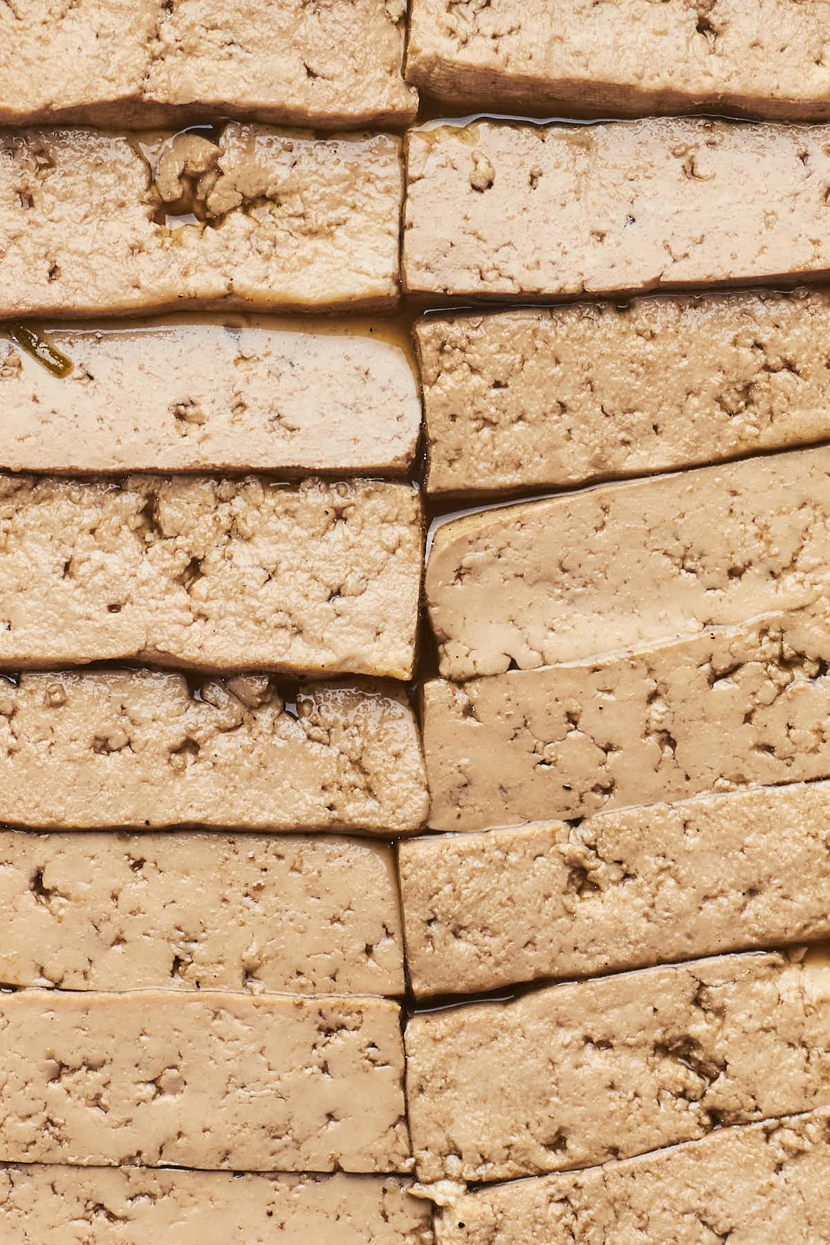 Close-up of stacked, slices of braised tofu, showing their textured.